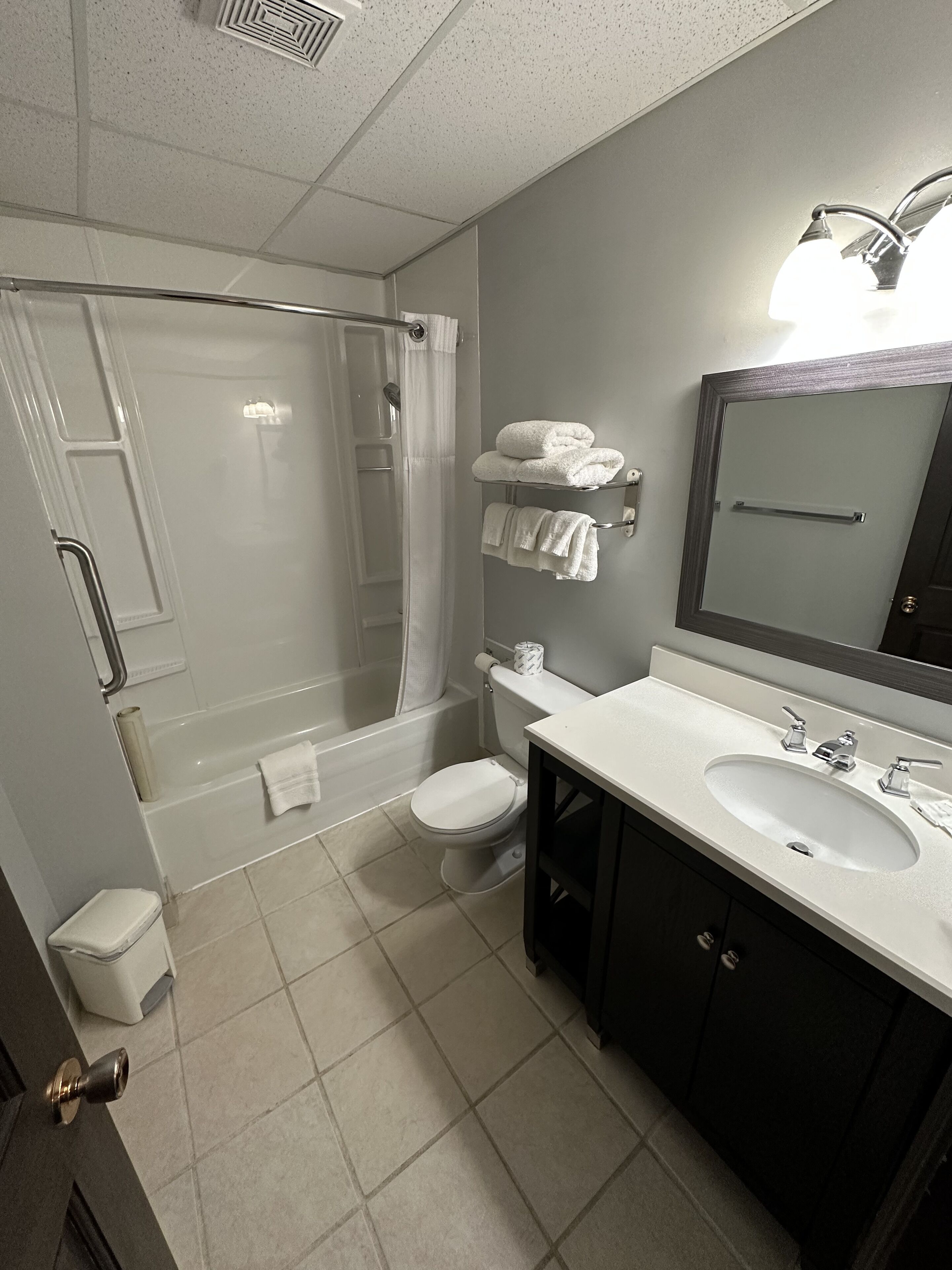 Un baño con ducha, inodoro, lavamanos y toallero.