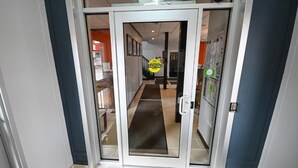 A hotel entrance with a glass door, a yellow caution sign, a staircase, and a carpeted path.