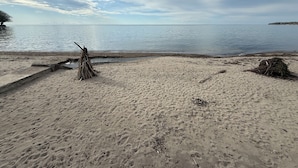 Ein sandiger Strand mit einer Betonstruktur und einem Holzstapel.