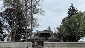 Ein zweistöckiges Gebäude mit einer Holzterrasse und einer Betontreppe, die zum Eingang führt.