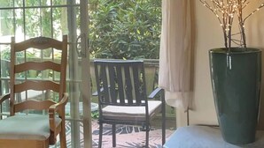 Ein Zimmer mit einem Holzbstuhl, einem Tisch und einer großen Vase mit Ästen.