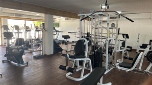 Een fitnessruimte met diverse trainingsapparaten, waaronder loopbanden, elliptische trainers en gewichtbanken.