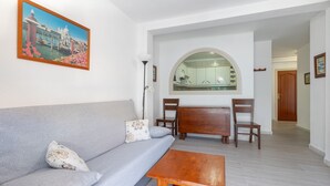 A living room with a sofa, a wooden coffee table, and a painting of a canal scene. - MONTEALBA - Cozy apartment very close to the beach, with free WiFi. (Fuengirola)