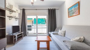 A modern living room with a grey sofa, a wooden coffee table, a TV on a stand, and a ceiling fan. - MONTEALBA - Cozy apartment very close to the beach, with free WiFi. (Fuengirola)