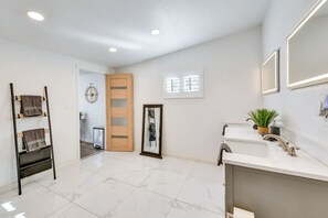 Modern bathroom with a large mirror, sink, and potted plant.