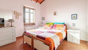 A bedroom with a bed, white nightstands, a dresser, a window, and a radiator. - The front, Cozy house in the hills in front of Forte dei Marmi (Pietrasanta)