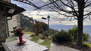 An outdoor patio with a table and chairs, overlooking a scenic view of the sea and hills. - The front, Cozy house in the hills in front of Forte dei Marmi (Pietrasanta)