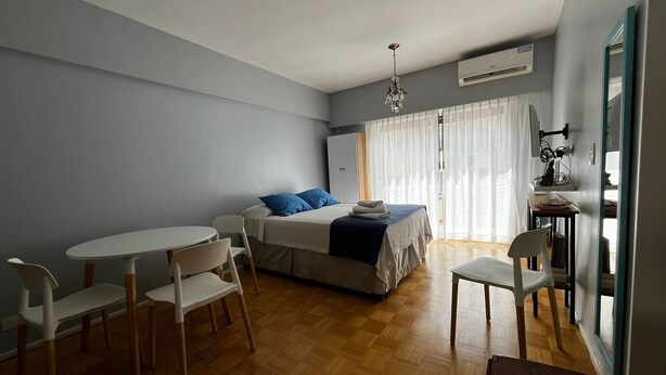 A compact room with a bed, a dining table, and chairs. - Cosy Studio in Recoleta, Buenos Aires. Walking distance from mayor attractions (CABA)