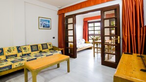 A room with a sofa, a wooden table, a dining table with chairs, and a large window with curtains. - 104 Andorra close to the beach (Playa de las Américas)