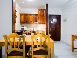 Un coin repas avec une table et des chaises en bois, un four à micro-ondes et un évier à l’arrière-plan.