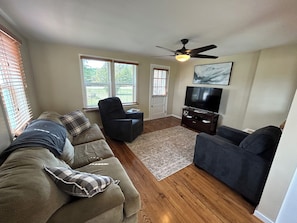 Relax in this stylish living room with a large window, flat-screen TV, and comfortable couches.