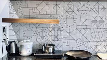 Eine Küche mit schwarzem Arbeitsplatz, Holzschränken, einer geometrischen Spritzschutzwand und einem Holzregal darüber.