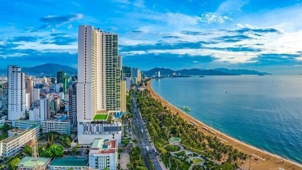 A coastal cityscape with high-rise buildings, a beach, and a clear sky.