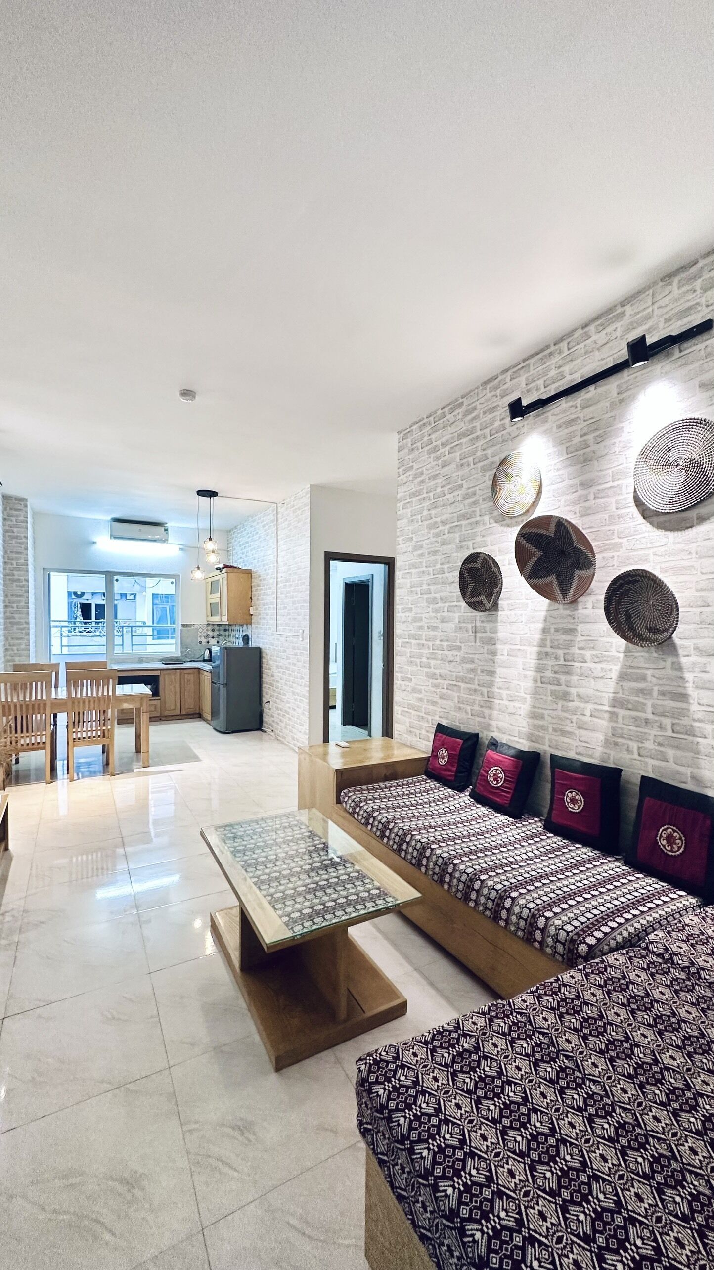 A modern living room with a sofa, coffee table, and a dining area with chairs and a table.