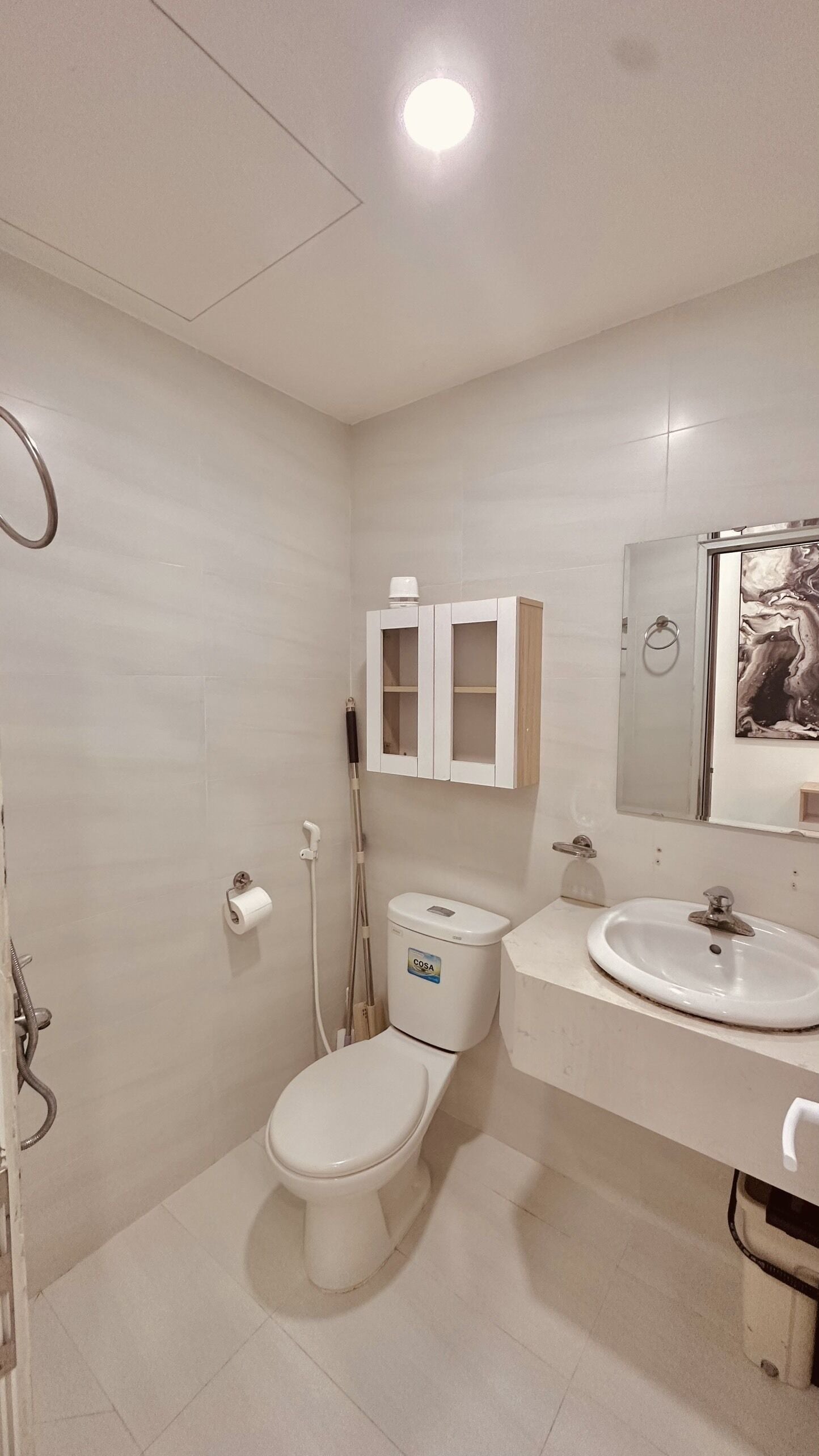 A bathroom with a toilet, a sink, a cabinet, and a shower.