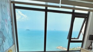 A room with a large bed, a desk, and a view of the sea.