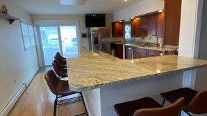 Een moderne keuken met een groot eiland, barkrukken en uitzicht op buiten.