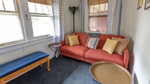 Quarto com sofá vermelho, um banco e um abajur.