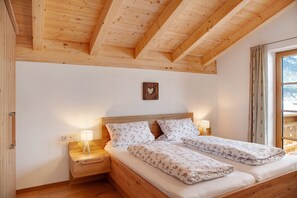Een slaapkamer met houten frame, een bed, nachtkastjes en een raam met gordijnen.