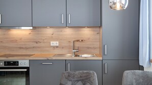 Eine moderne Küche mit grauen Schränken, einer Edelstahlspüle und einer Holzausziehtafel.