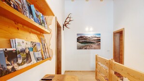 Un couloir avec des étagères en bois, un banc en bois et un tableau encadré accroché au mur.