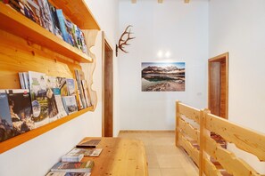Un couloir avec des étagères en bois, un banc en bois et un tableau encadré accroché au mur.