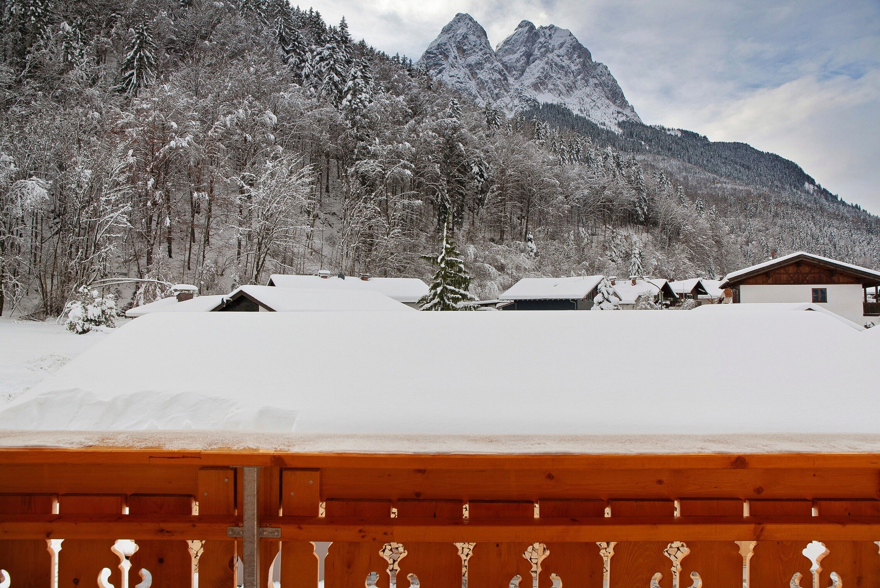 A snowy mountain landscape with a wooden fence in the foreground.