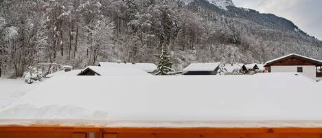 A snowy mountain landscape with a wooden fence in the foreground.