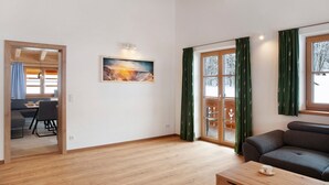 Un salon moderne avec un canapé, un coin repas avec des chaises et un tableau accroché au mur.