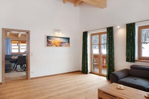 Un salon moderne avec un canapé, un coin repas avec des chaises et un tableau accroché au mur.
