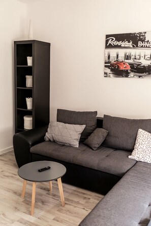 A modern living room with a grey sofa, a black coffee table, and a black bookshelf. - Apartment "In Dattenberg" with Wi-Fi (Dattenberg)