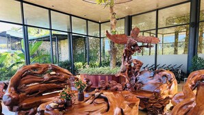 A spacious indoor area with large windows, a central wooden sculpture, and a seating area with a table. - Vigolando Van Ho Resort (Van Ho)