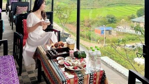 A dining area with a view of green hills, a fan, and a table with food and drinks. - Vigolando Van Ho Resort (Van Ho)