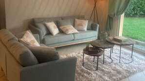 A modern living room with a sectional sofa, a coffee table, and a floor lamp. - Villa Morgon (SAVINES LE LAC)