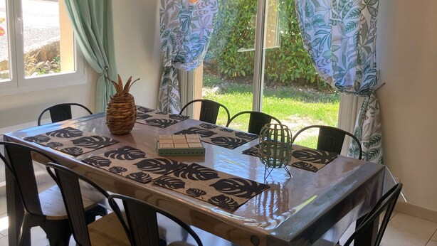 A dining area with a wooden table, black chairs, and a woven centerpiece. - Villa Morgon (SAVINES LE LAC)
