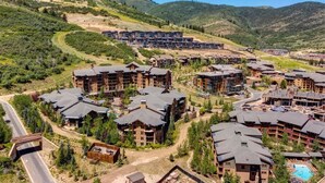 A resort with multiple buildings, a pool, and a mountainous backdrop. - Abode at First Dawn, ski-in/ski-out, hot tub, sauna, resort access (Park City)