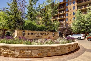 Um sinal de pedra com 'HYATT CENTRIC PARK CITY' e uma área ajardinada com plantas.