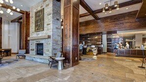 A lobby with stone walls, wooden beams, a fireplace, seating area, and a reception desk. - Abode at First Dawn, ski-in/ski-out, hot tub, sauna, resort access (Park City)