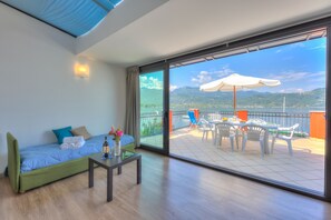 A modern room with a sofa, a small table, and a balcony with a table and chairs.
