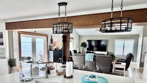 Una cucina moderna con mobili bianchi, una grande isola e lampadari neri a sospensione.