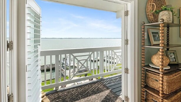 Un balcone con vista sull'acqua, una ringhiera bianca e cesti di vimini su uno scaffale.