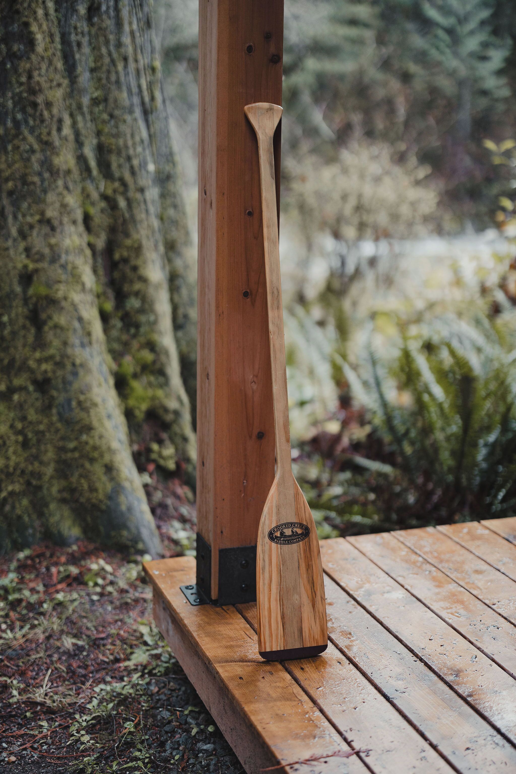 Une table en bois avec une pagaie appuyée contre un poteau en bois.