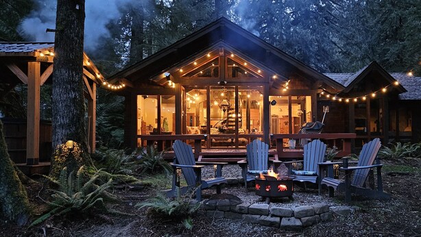 A cabin with a deck, outdoor seating, and a fire pit.