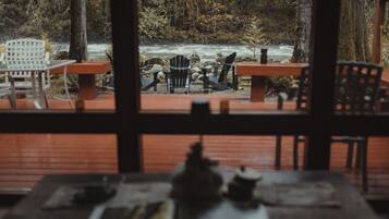 A wooden deck with outdoor seating overlooking a river.