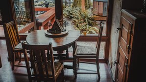 A wooden dining table with chairs, a bench, and a view of a forested area through large windows.