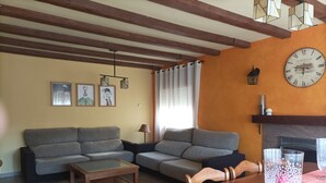 A living room with a sofa set, a coffee table, a dining table with chairs, a fireplace, and a wall clock. - House with large garden and fireplace, ideal for families, pet friendly. (Narros de Cuéllar)