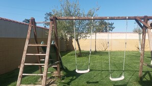 A wooden swing set in a backyard with a brick wall and a ladder. - House with large garden and fireplace, ideal for families, pet friendly. (Narros de Cuéllar)