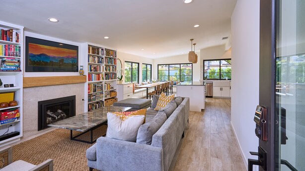 A spacious living room with a fireplace, a large bookshelf, a sofa, and a dining area. - Breathtaking Private Beach Getaway (Ventura)