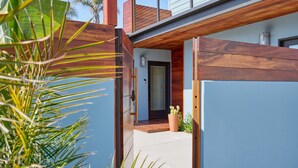 A modern house with a wooden deck, a potted plant, and a clear sky. - Breathtaking Private Beach Getaway (Ventura)
