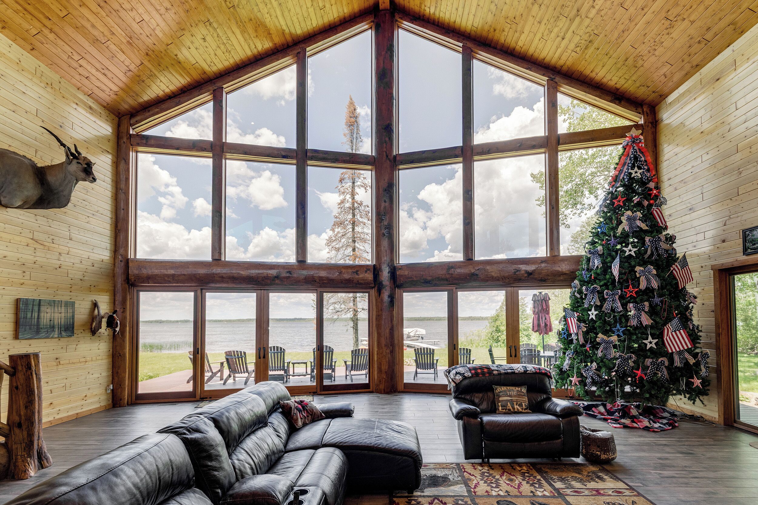 Une pièce spacieuse avec une grande fenêtre, un sapin de Noël, des meubles en cuir et une vue sur l’extérieur.